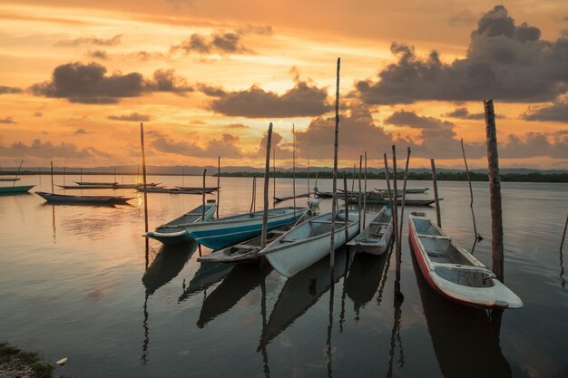 Paisaje con puesta de sol con canoas de pesca en la orilla del río.