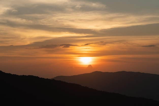 Paisaje de puesta de sol con iluminación dorada de montaña y sol bajo un cielo nocturno colorido y vibrante en las montañas Naturaleza cielo de montaña y nubes concepto de puesta de sol