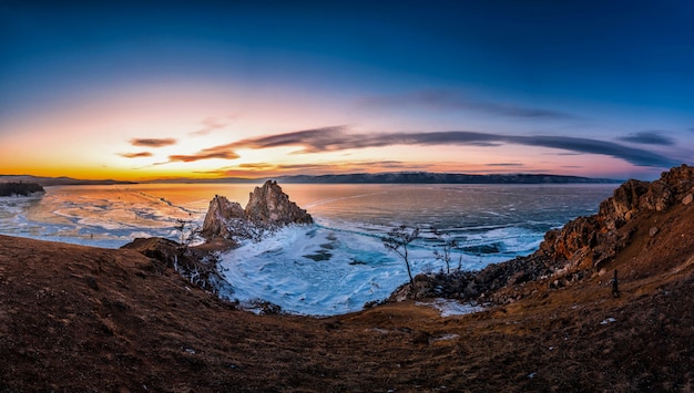 Paisaje de la roca de Shamanka en la puesta del sol con hielo de fractura natural en agua congelada en el lago Baikal, Siberia, Rusia.