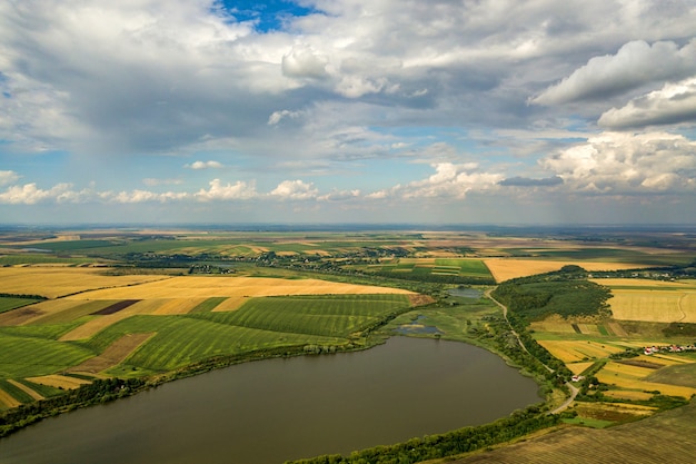 Paisaje rural aéreo con campos de agricultura parcheado amarillo y cielo azul con nubes blancas.