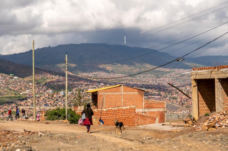 Paisaje rural boliviano mujer indígena caminando por una montaña con una colina llena de casas