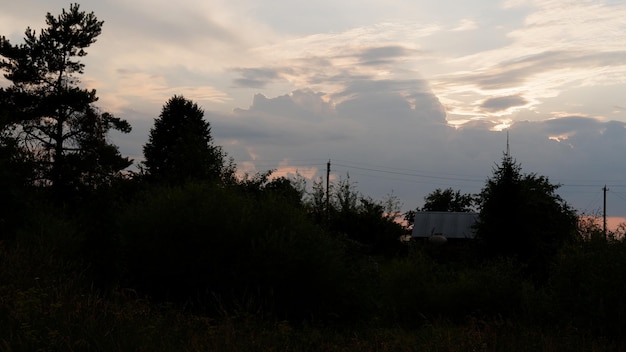 Paisaje rural con campo al atardecer y pueblo en la región de vologda de fondo