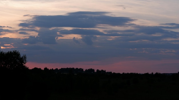 Paisaje rural con campo al atardecer y pueblo en la región de vologda de fondo