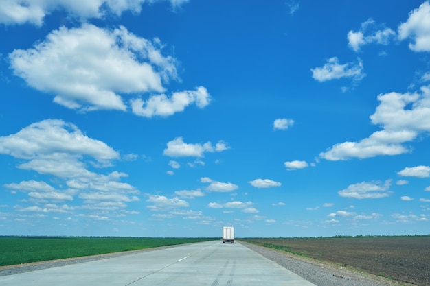 Paisaje rural con carretera de hormigón y camión lejano en movimiento