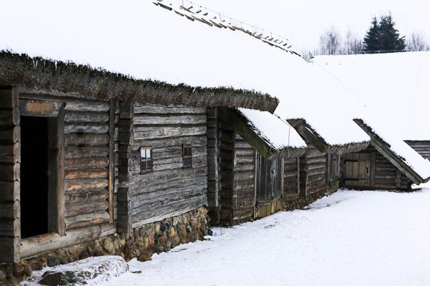 Paisaje ruso de invierno Una vieja cabaña de madera una casa de troncos con techo de paja Aldea rusa abandonada cubierta de nieve Casa de troncos con granero