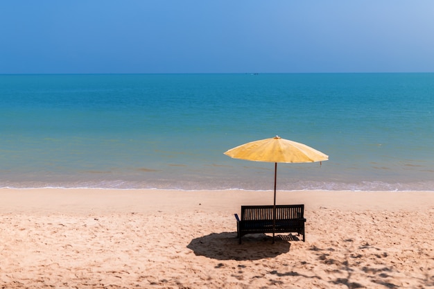 Paisaje de una silla y sombrilla de playa en la playa.