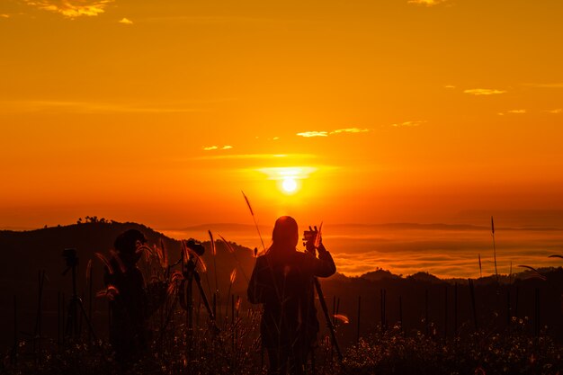 Foto paisaje de silueta en la mañana, turista toma fotos del amanecer y la niebla en la montaña