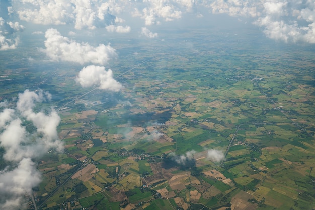 Paisaje de tierra visto desde el avión. Superficie de la tierra debajo de las nubes blancas de la vista aérea.