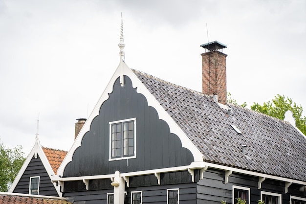 Paisaje típico holandés Molino de viento holandés antiguo tradicional con casas antiguas contra el cielo azul nublado en el pueblo de Zaanse Schans Países Bajos Famoso lugar turístico Ovejas pastando en la hierba verde