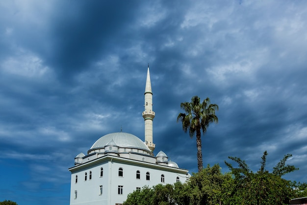 Paisaje turco con mezquita blanca y minarete sobre un fondo de cielo nublado azul oscuro