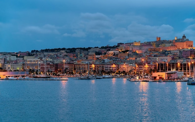 Paisaje urbano con la ciudad vieja y el puerto deportivo de Cerdeña con barcos en el mar Mediterráneo en Cagliari, isla del sur de Cerdeña en Italia en verano. Ver el puerto de la ciudad con yates y barcos. Al anochecer