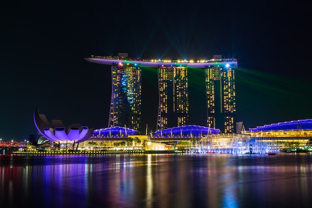 El paisaje urbano del horizonte de Singapur con la luz y el agua muestran alrededor de la bahía del puerto deportivo en la noche.