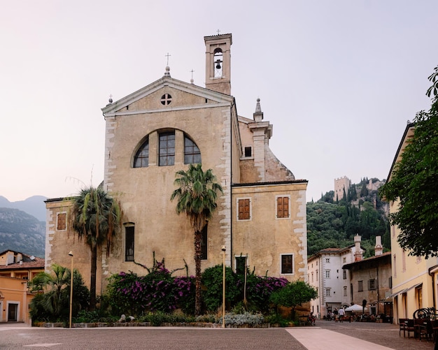 Foto paisaje urbano con la iglesia santa maria assunta sobre roca en el valle de sarca cerca del lago de garda de trentino en italia. calle con catedral en la montaña en la ciudad de arco en trento cerca de riva del garda