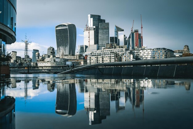 Paisaje urbano de Londres con muchos rascacielos modernos reflejados en el agua durante el día en el Reino Unido