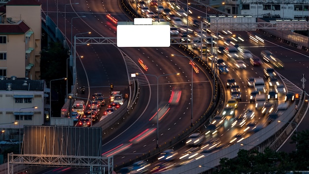 Paisaje urbano y la luz del camino de la noche en larga exposición con cartelera de rascacielos