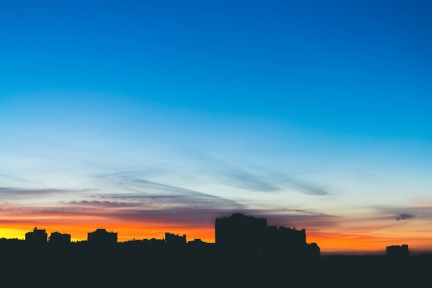 Paisaje urbano con maravilloso amanecer vívido multicolor. Increíble espectacular cielo azul con nubes púrpuras y violetas sobre siluetas oscuras de los edificios de la ciudad