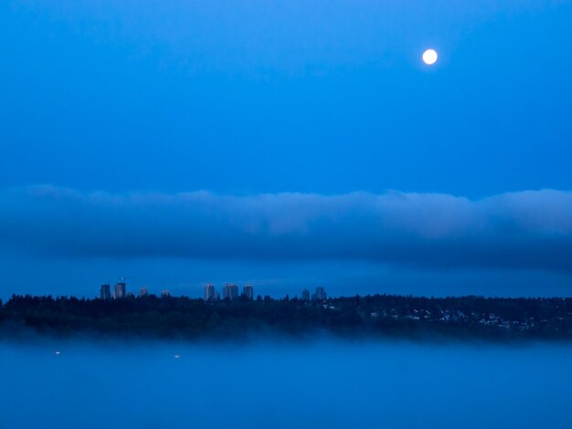 Foto paisaje urbano en la noche con luna llena en el cielo