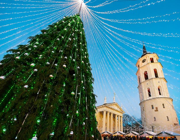 Paisaje urbano nocturno con mercado navideño en la plaza de la catedral en Winter Vilnius, Lituania. Feria de Adviento Decoración y Puestos con Artículos de Artesanía en el Bazar. calle lituana. Foco seleccionado