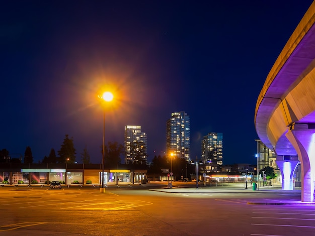 Foto paisaje urbano nocturno con tren aéreo y luz de la calle brillante sobre la plaza