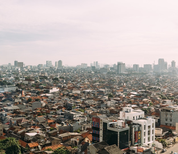 Paisaje urbano de Yakarta con rascacielos y edificios locales con techos de teja roja.