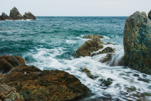 Paisaje de verano de mar con olas borrosas, rocas en la playa