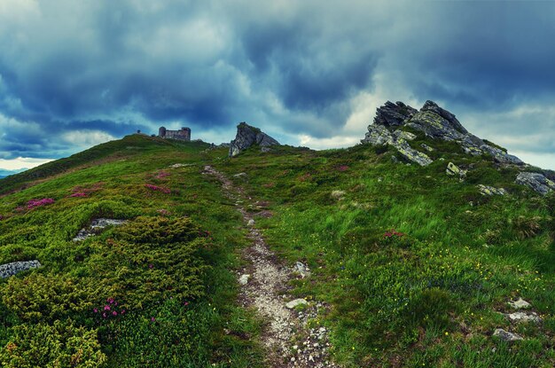 Paisaje de verano de las montañas de los Cárpatos con un cielo dramático y un antiguo observatorio en el fondo de viaje natural superior