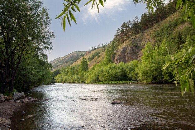 Paisaje de verano un río entre montañas y rocas contra un cielo azul con nubes con espacio de copia Turismo recreación activa