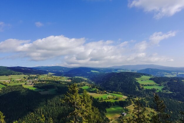 Paisaje verde con campos, bosques y montañas con nubes en el cielo azul en austria