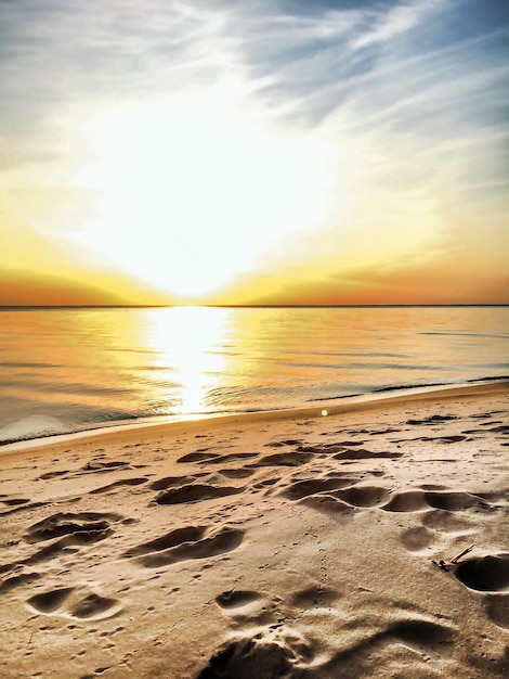 Foto paisaje vertical amanecer junto al mar cielo azul y arena amarilla