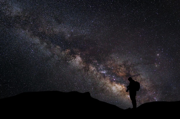 Paisaje con vía láctea Cielo nocturno con estrellas y silueta de un fotógrafo de pie