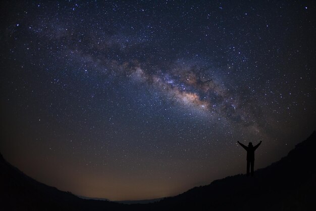 Paisaje con vía láctea Cielo nocturno con estrellas y silueta de gente feliz de pie en la montaña