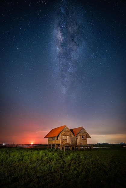 Paisaje de la vía láctea sobre la casa gemela abandonada cerca de Chalerm Phra Kiat road en Thale Noi, Phatthalung, Tailandia