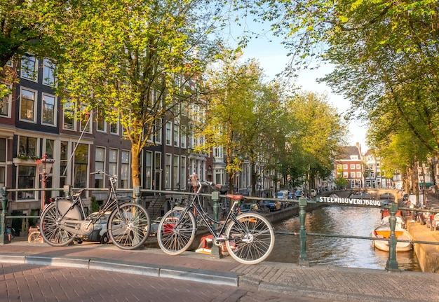 Países Bajos Día soleado de primavera en Ámsterdam Bicicletas aparcadas en un puente del canal con un cartel holandés Puente de piedra