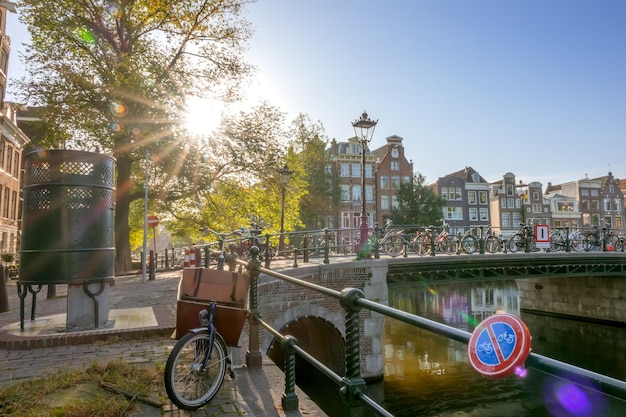 Países Bajos Mañana soleada en Amsterdam Casas tradicionales en el canal Muchas bicicletas cerca de la cerca del puente Baño masculino de la calle