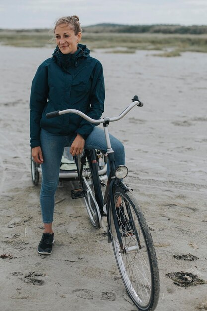 Países Bajos, Schiermonnikoog, mujer con bicicleta y remolque en la playa