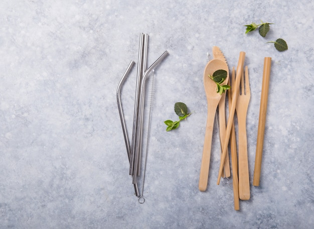 Paja y cubiertos de metal reutilizables ecológicos (cuchara, cuchillo, tenedor) en la mesa de madera. concepto de cero residuos