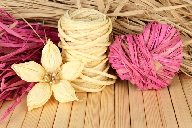 Paja decorativa hecha a mano, flor y corazón de paja, sobre fondo de madera