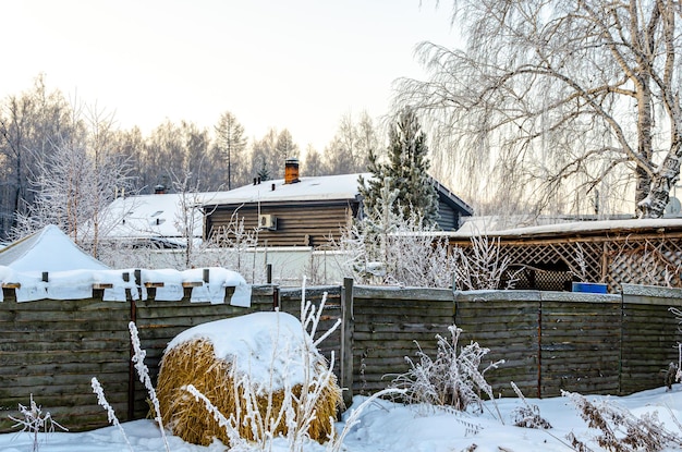 Un pajar bajo la nieve cerca de una casa en el pueblo.
