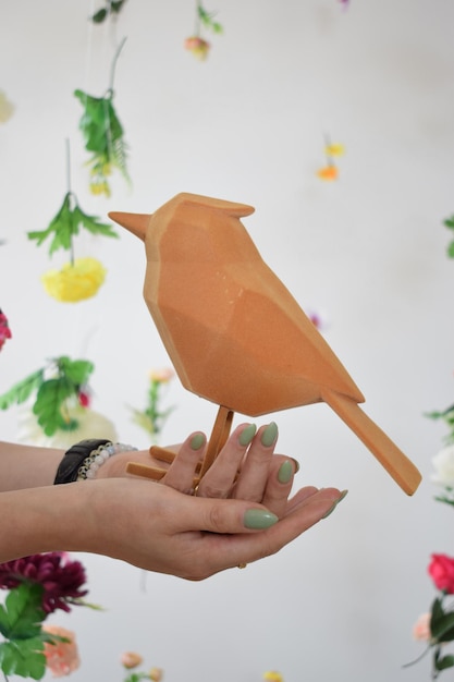 Pájaro para decoración en manos de una joven sobre un fondo floral