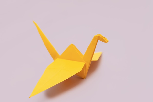 Pájaro de origami amarillo en la pared púrpura