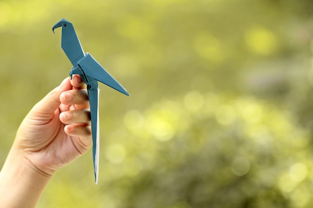 Pájaro de origami en mano de mujer sobre fondo natural