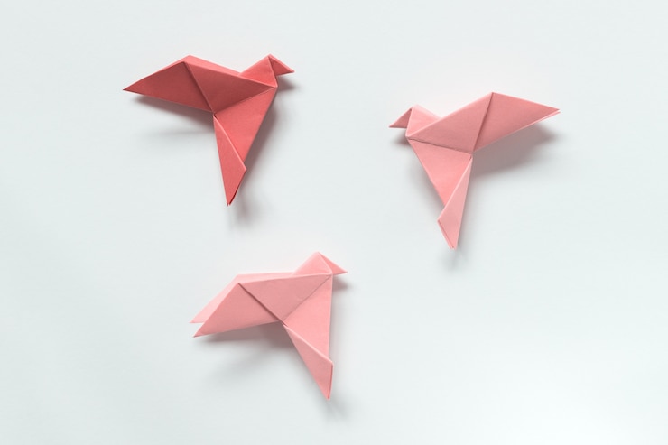 Foto pájaros rosados de diferentes tonos. origami. el concepto de libertad, inspiración.