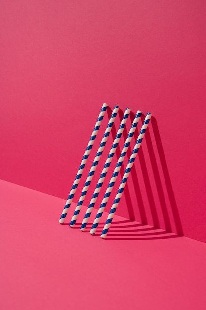 Foto pajitas de papel a rayas azules apoyadas en la pared magenta concepto mínimo