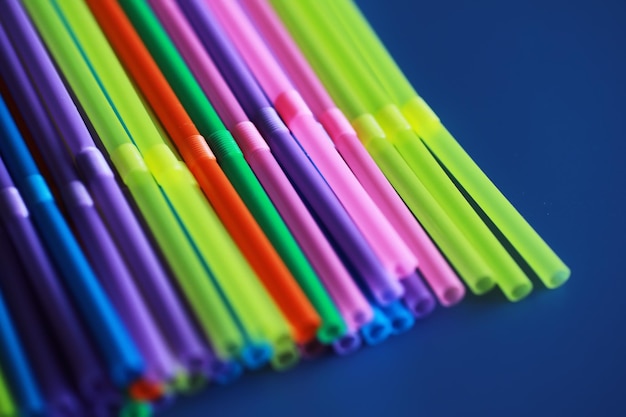 Las pajitas de plástico de colores se cierran como túbulos de color de fondo para jugos y cócteles en una mesa de madera negra