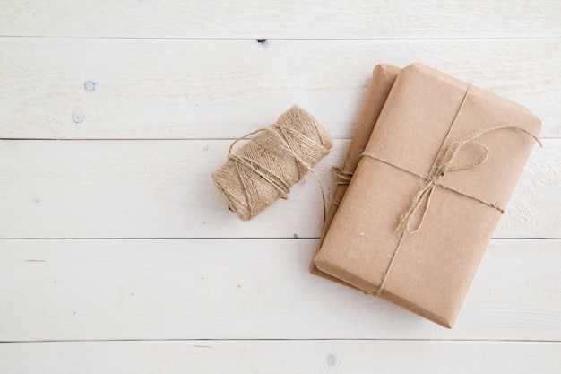 Paket, Geschenk verpackt im umweltfreundlichen Papier und in der Schnur für das Verpacken auf hellem hölzernem Hintergrund. der Blick von oben