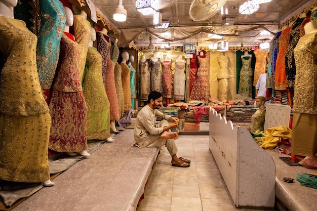 Pakistanischer Mann, der bunte Stoffe und Kleider auf dem Qissa Khwani Bazaar in Peshawar Pakistan verkauft