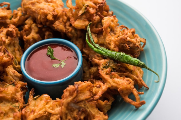 Pakora de cebola frita ou Pyaj Pakoda, também conhecido como Crispy Kanda bhaji / Bhajji / bajji, lanche da hora do chá indiano favorito durante a estação das chuvas. servido com ketchup de tomate