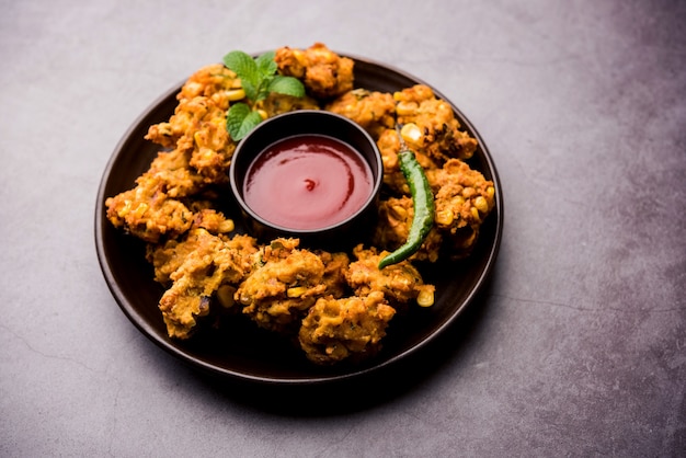 Pakora o pakoda de maíz crujiente, bhajji, Bhaji, bajji o pattice. servido con salsa de tomate