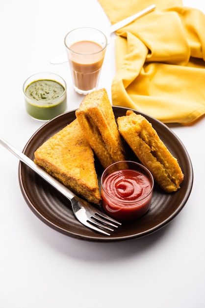 Pakora de pan de sándwich o pakoda en forma de triángulo servido con salsa de tomate, salsa picante verde, refrigerio indio popular a la hora del té