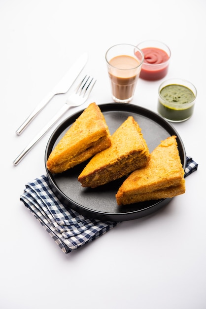 Pakora de pan de sándwich o pakoda en forma de triángulo servido con salsa de tomate, salsa picante verde, refrigerio indio popular a la hora del té